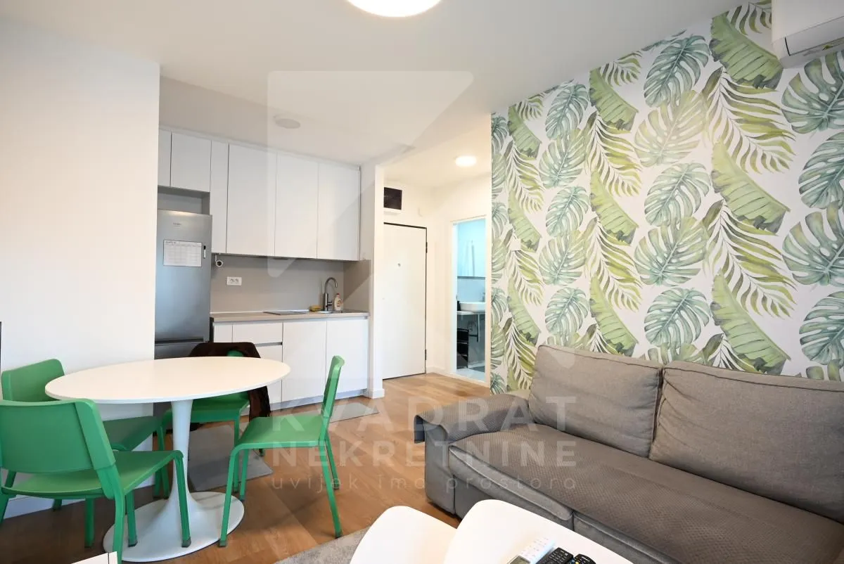Living room with a sofa, dining area, and fitted kitchen in the background.