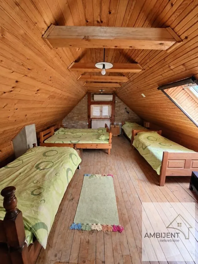 Potkrovlje opremljeno sa nekoliko drvenih kreveta i obloženo drvenim panelima.