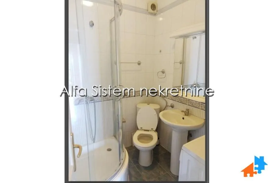 Smaller bathroom with a shower cabin, washbasin, and toilet.