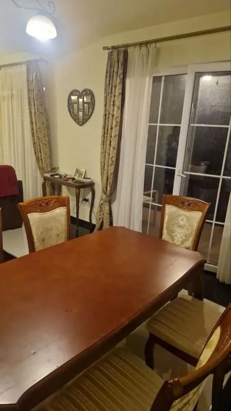Dining area with a wooden table and chairs, next to the balcony door.