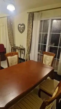 Dining area with a wooden table and chairs, next to the balcony door. - image 9