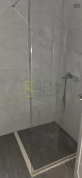 Moderno kupatilo sa tuš kabinom obloženom mermernim pločicama. - image 7