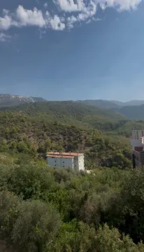 Pogled iz apartmana na šumovite planine i okolne zgrade. - image 11