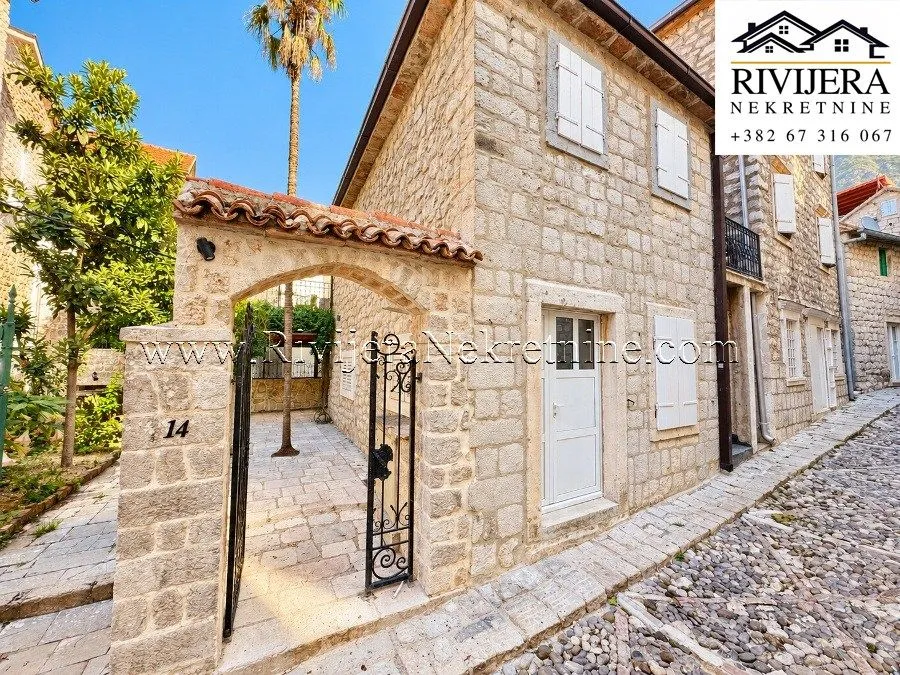 Exterior view of a traditional stone house with a courtyard and entrance gate.