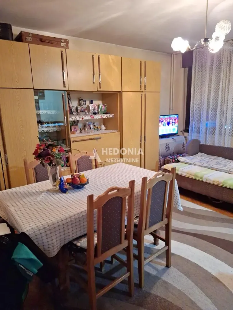 Living room with dining area, seating set, and a large wooden wardrobe.