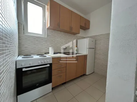 Manja kuhinja sa drvenim elementima, šporetom i frižiderom. - image 3