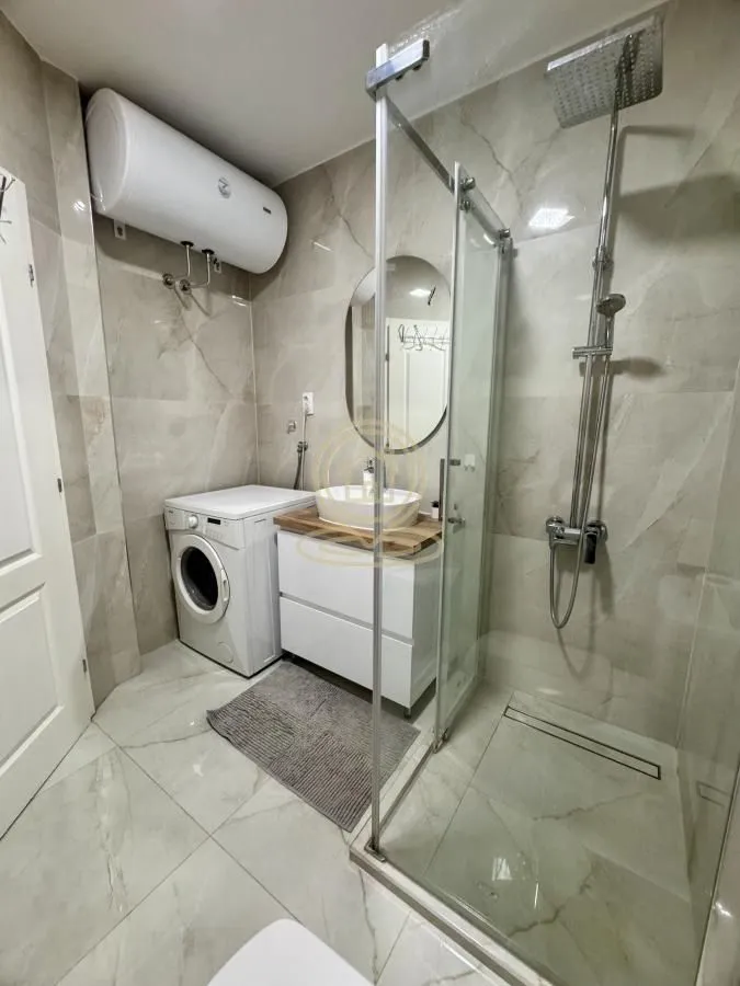 Modern bathroom equipped with a shower cabin, washbasin, and washing machine.