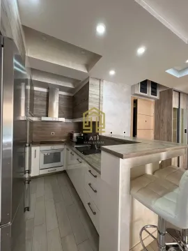 Modern kitchen with a bar counter and built-in appliances. - image 5