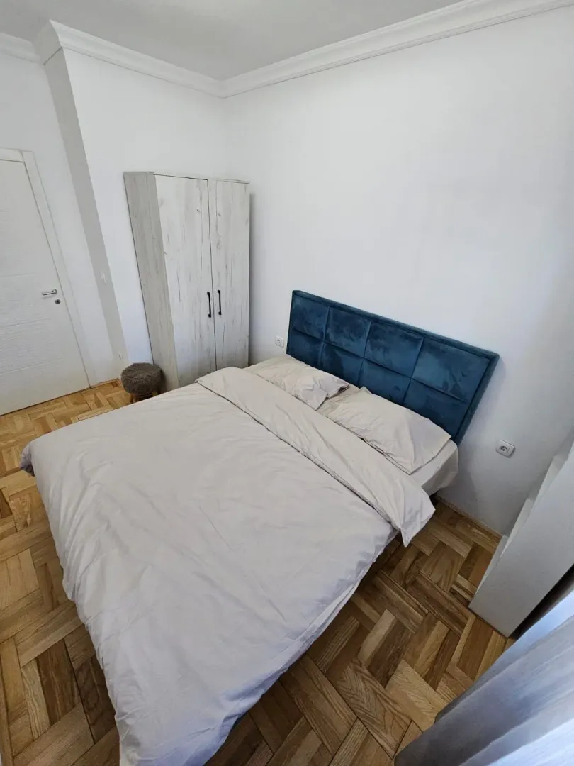 Uređena spavaća soba sa bračnim krevetom i ormarom.