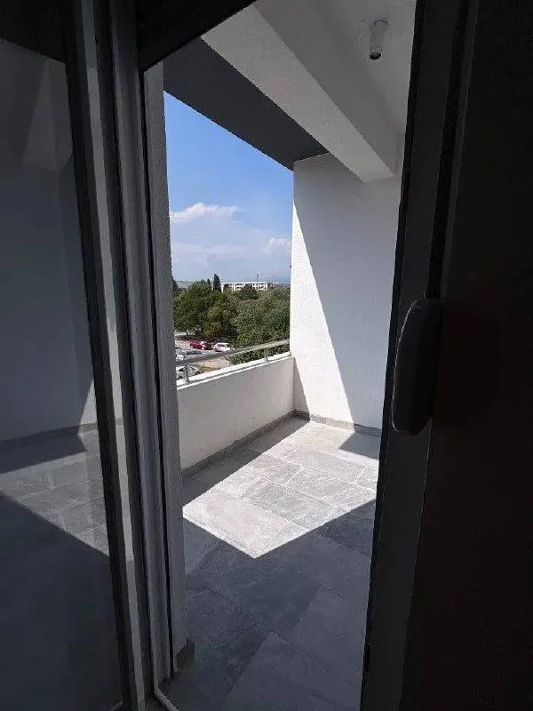 Pogled na prostrani balkon sa popločanim podom i ogradom.