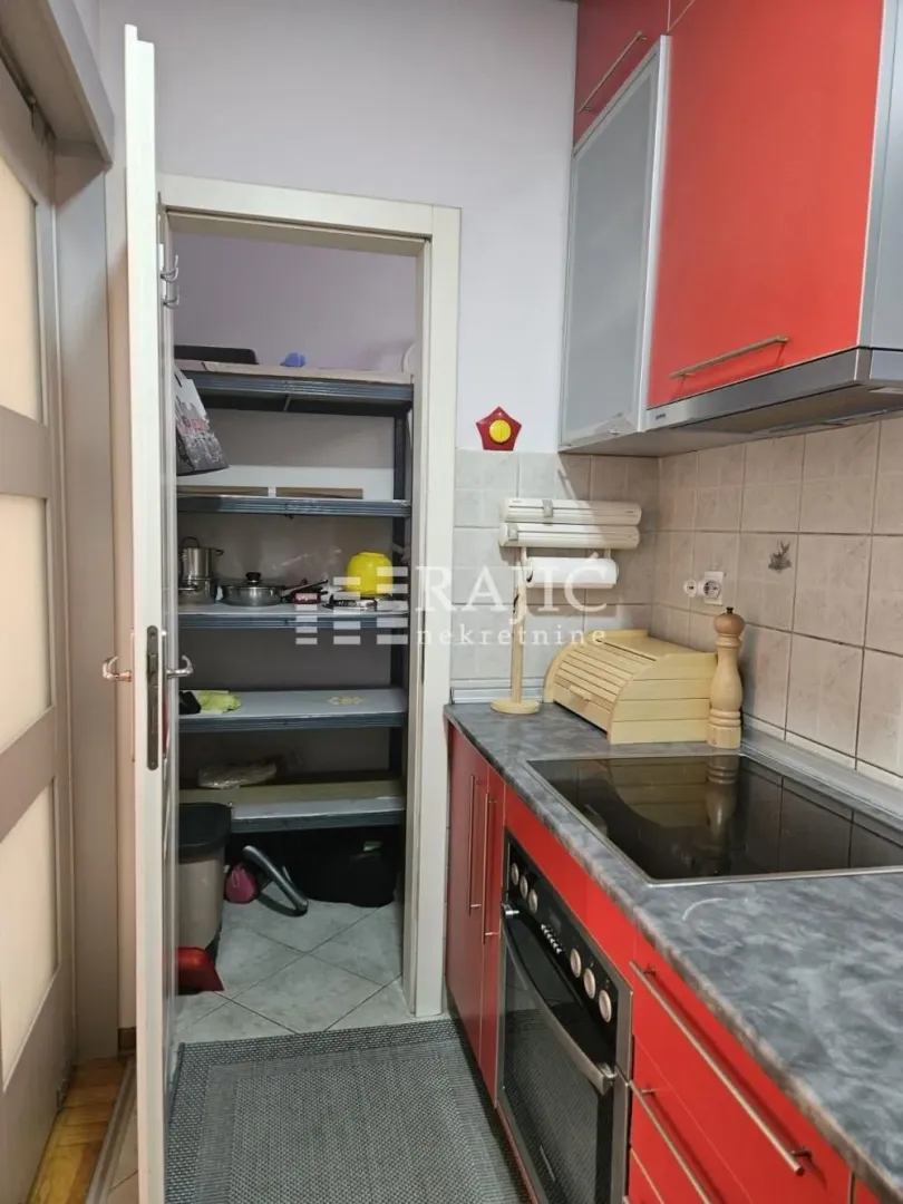 Small kitchen with red cabinets and a pantry.