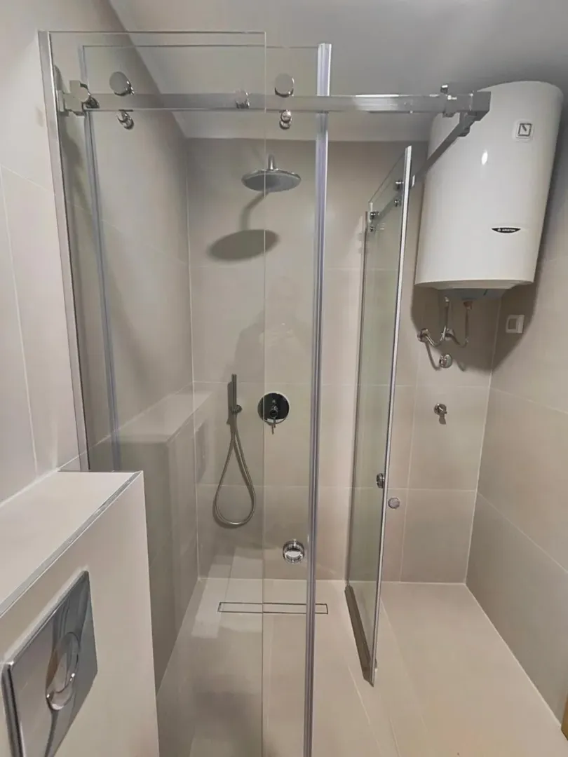 Modern bathroom with a shower cabin and water heater.