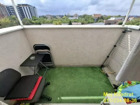 Manji namešteni balkon sa veštačkom travom i pogledom na grad. - image 9