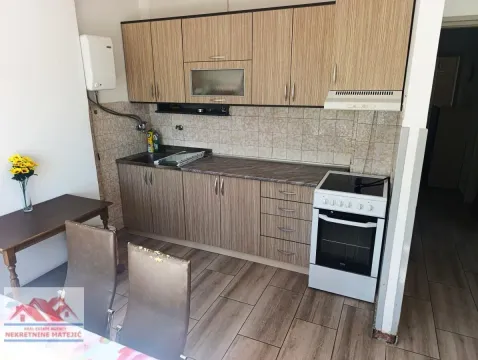 Small kitchen with wooden cabinetry, stove, and dining table. - image 15