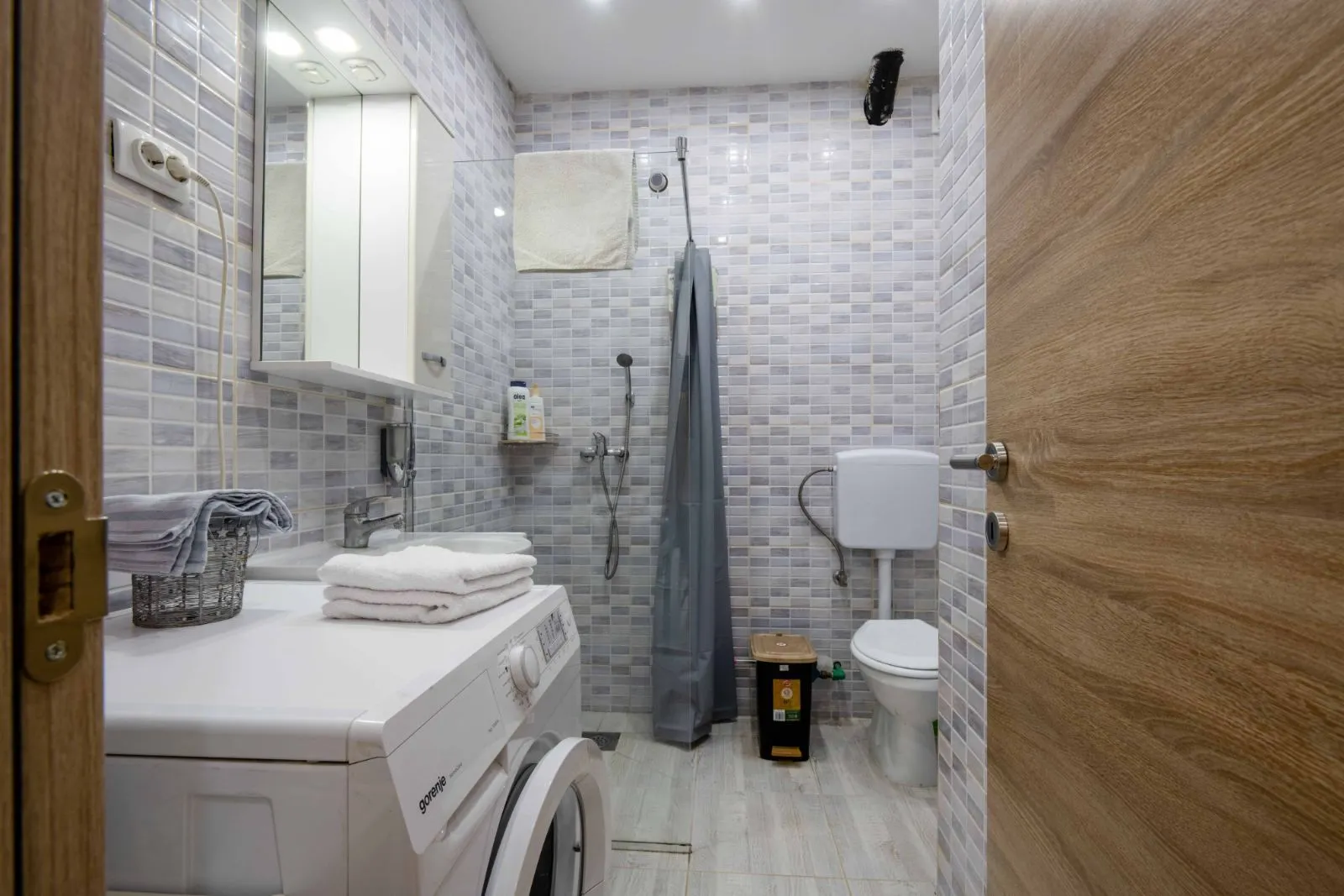 Small bathroom with a shower cabin, sink, toilet, and washing machine.