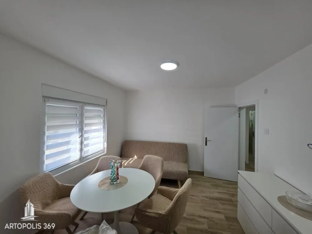 Living room with a dining table and chairs, a sofa, and a window with blinds.