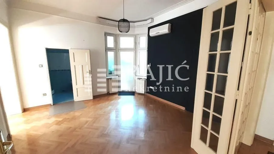 Empty living room with wooden parquet flooring and a black wall.