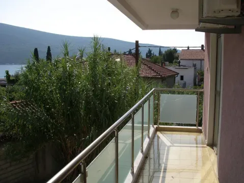 Balkon sa staklenom ogradom i pogledom na more u daljini. - image 5