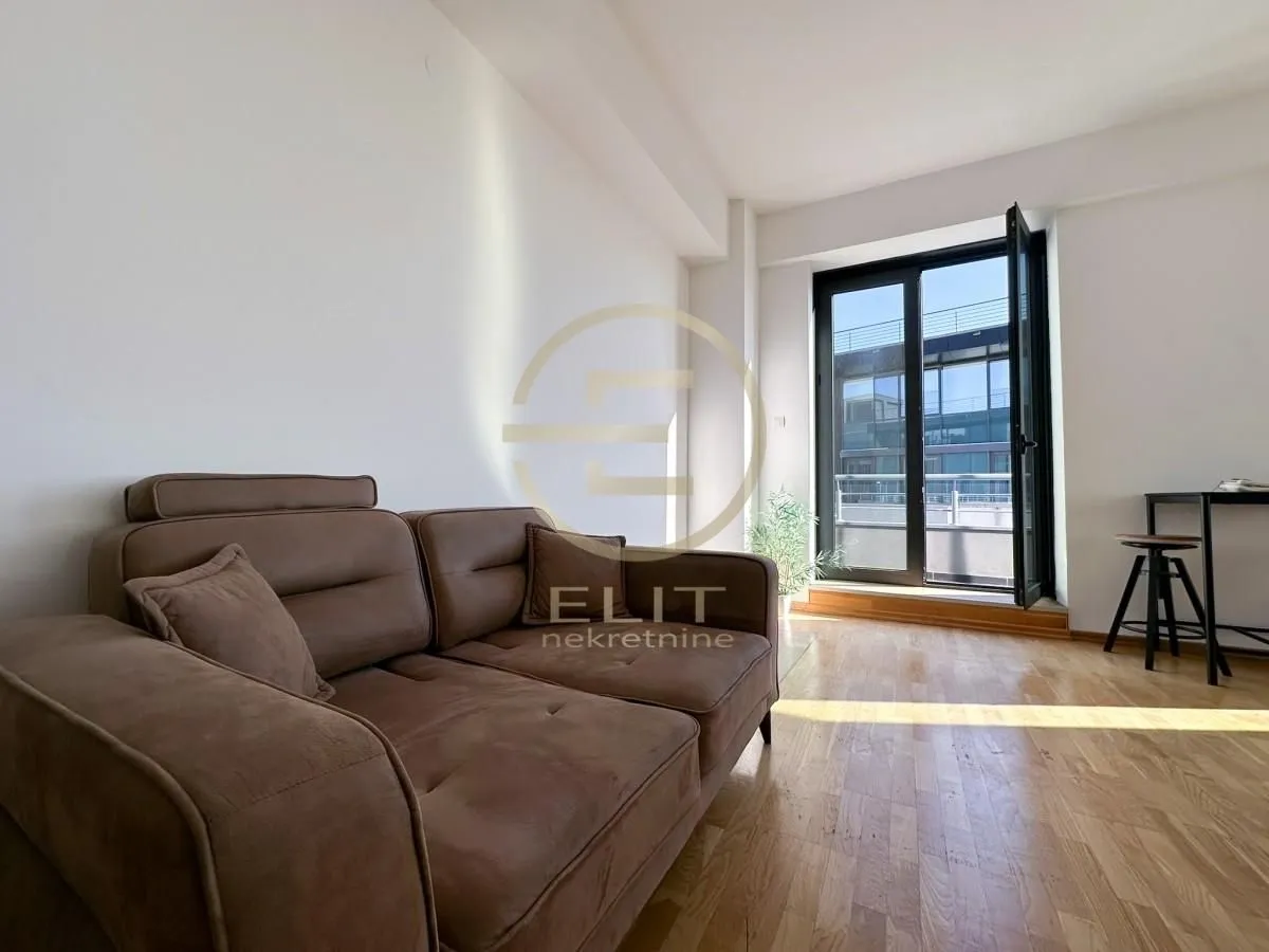 Living room with a brown sofa and access to the terrace.