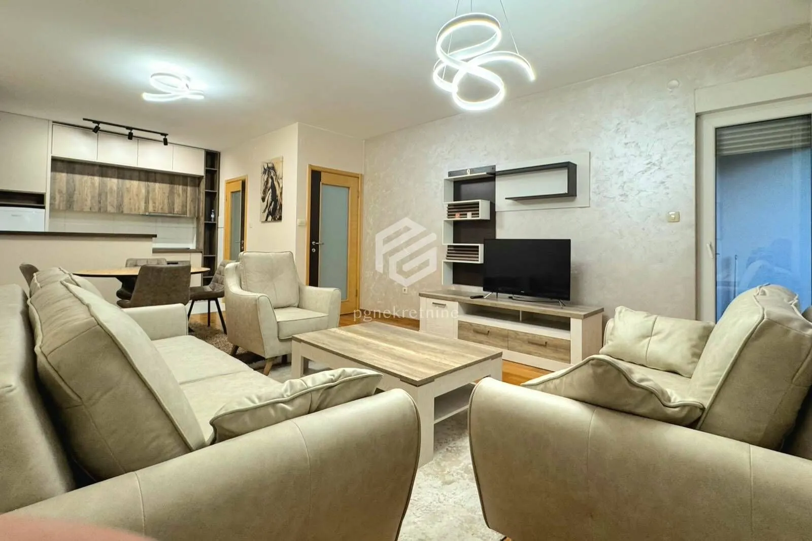 Spacious living room with sofa set, TV, and dining area in the background.