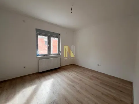 Prazna soba sa belim zidovima, laminatom i radijatorom ispod prozora. - image 14