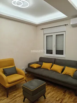 Dnevna soba sa sivom garniturom, žutim foteljama i drvenim podom. - image 3
