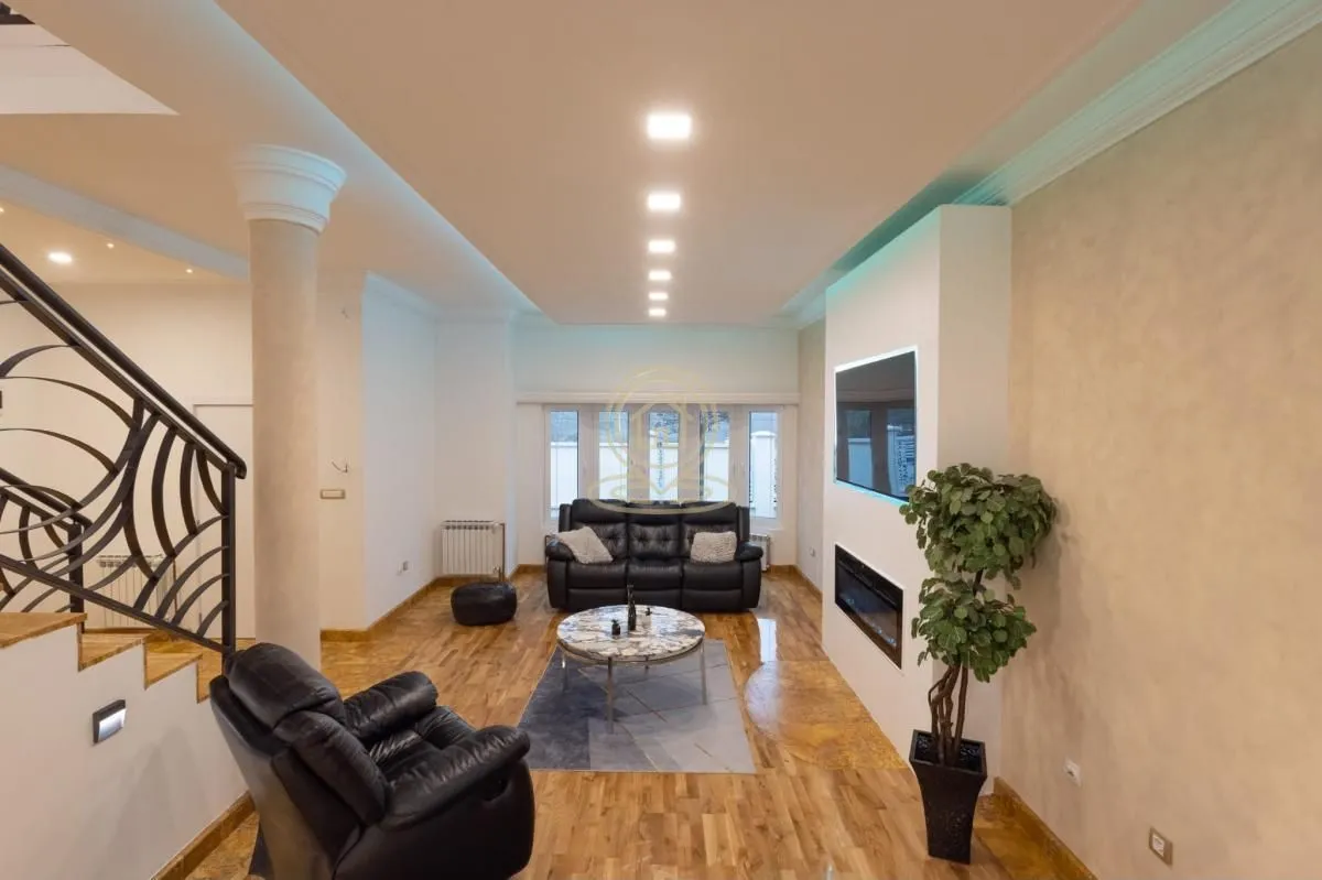 Spacious living room with sofa set, fireplace, TV, and stairs.