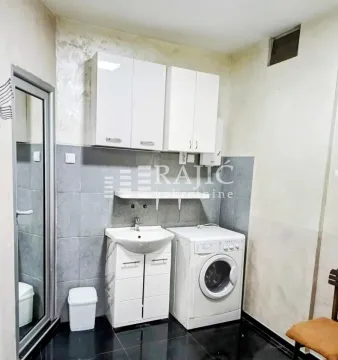 Small bathroom with a sink, white cabinet, washing machine, and upper wall cabinets. - image 7