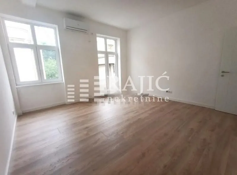 Empty room with laminate flooring and white walls.
