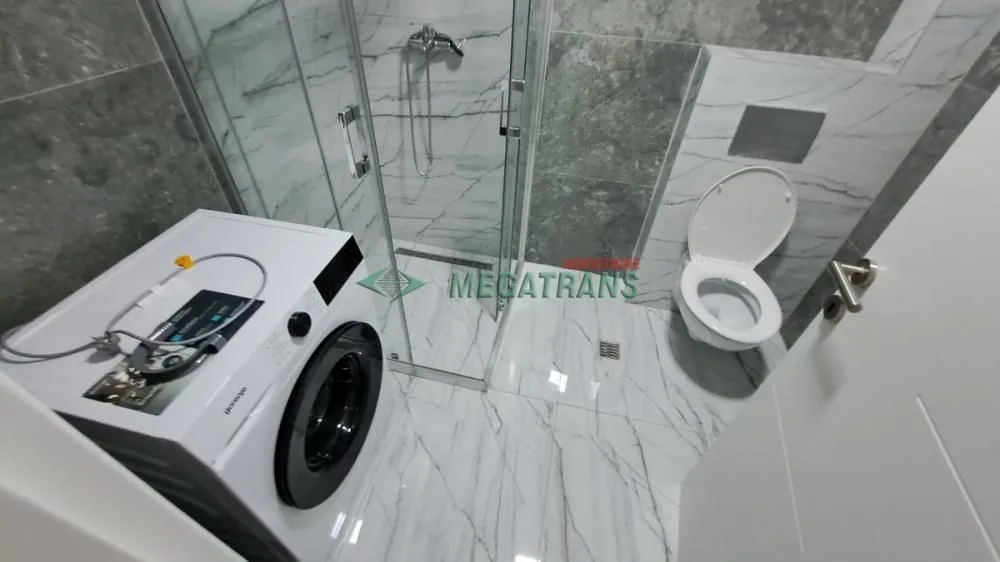 Moderno kupatilo sa tuš kabinom, wc šoljom i veš mašinom.