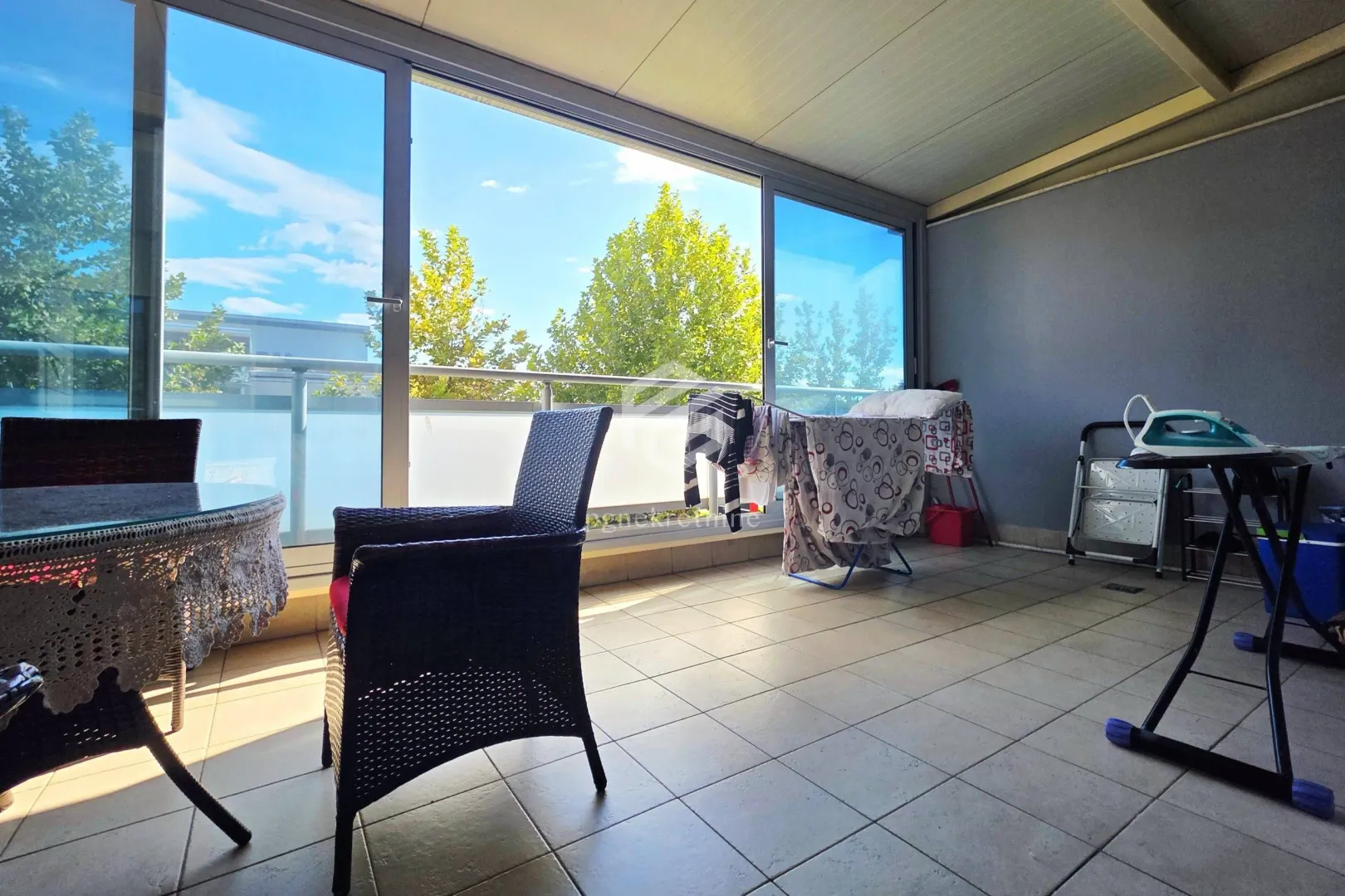 Covered terrace with a table, chairs, and a clothes drying rack.