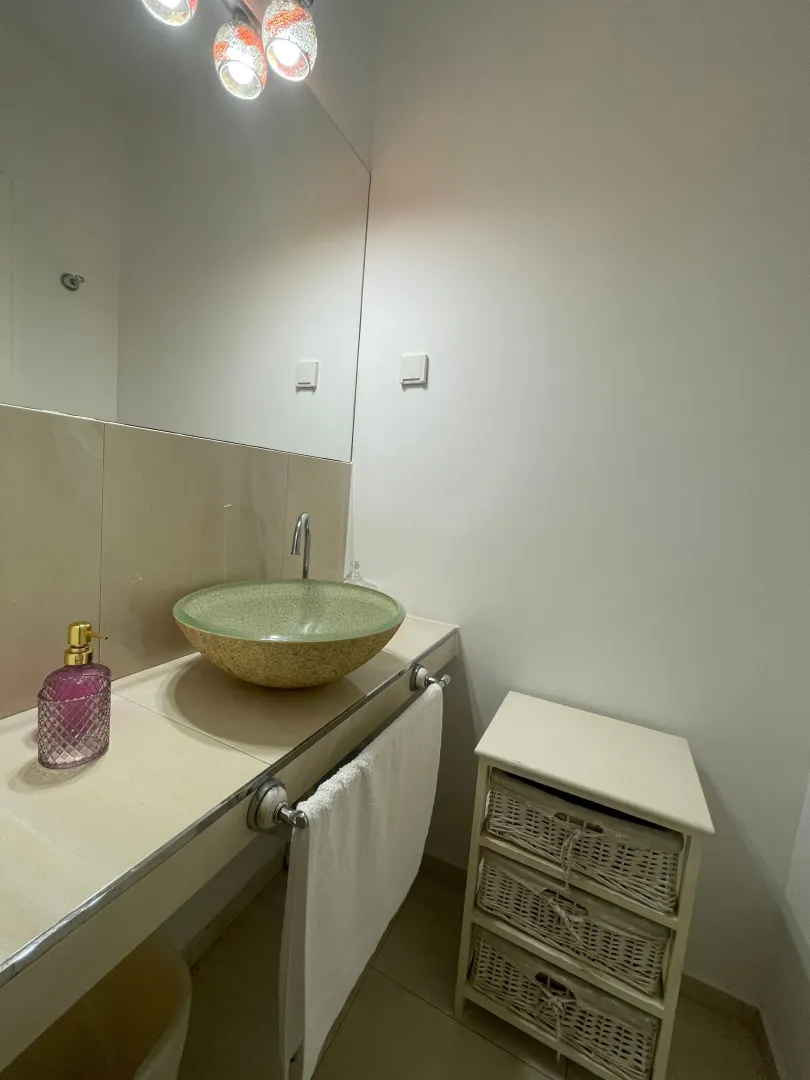 Compact bathroom with a vessel sink, mirror, and a small drawer unit.