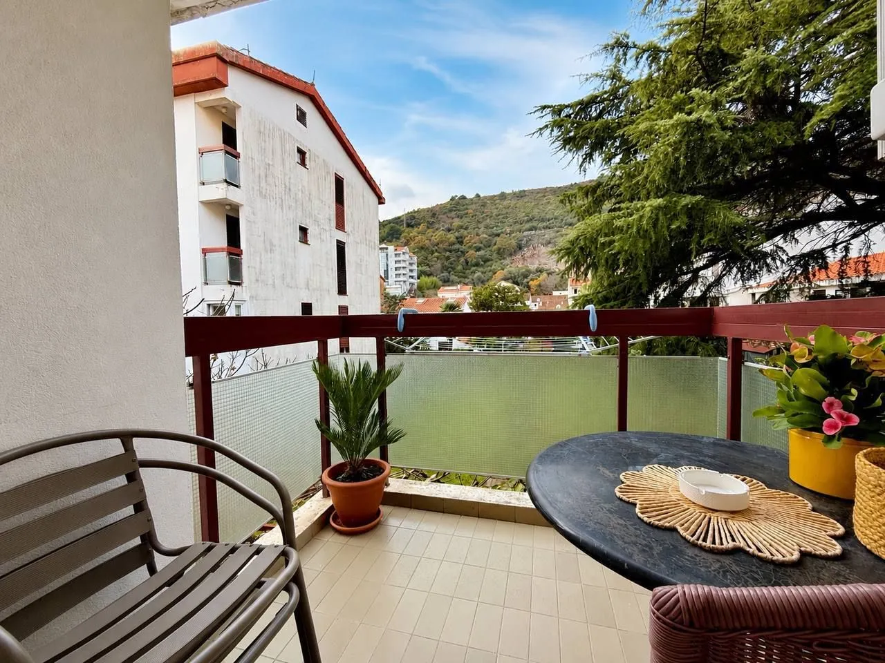 Furnished balcony with a table, chairs, and potted plants.