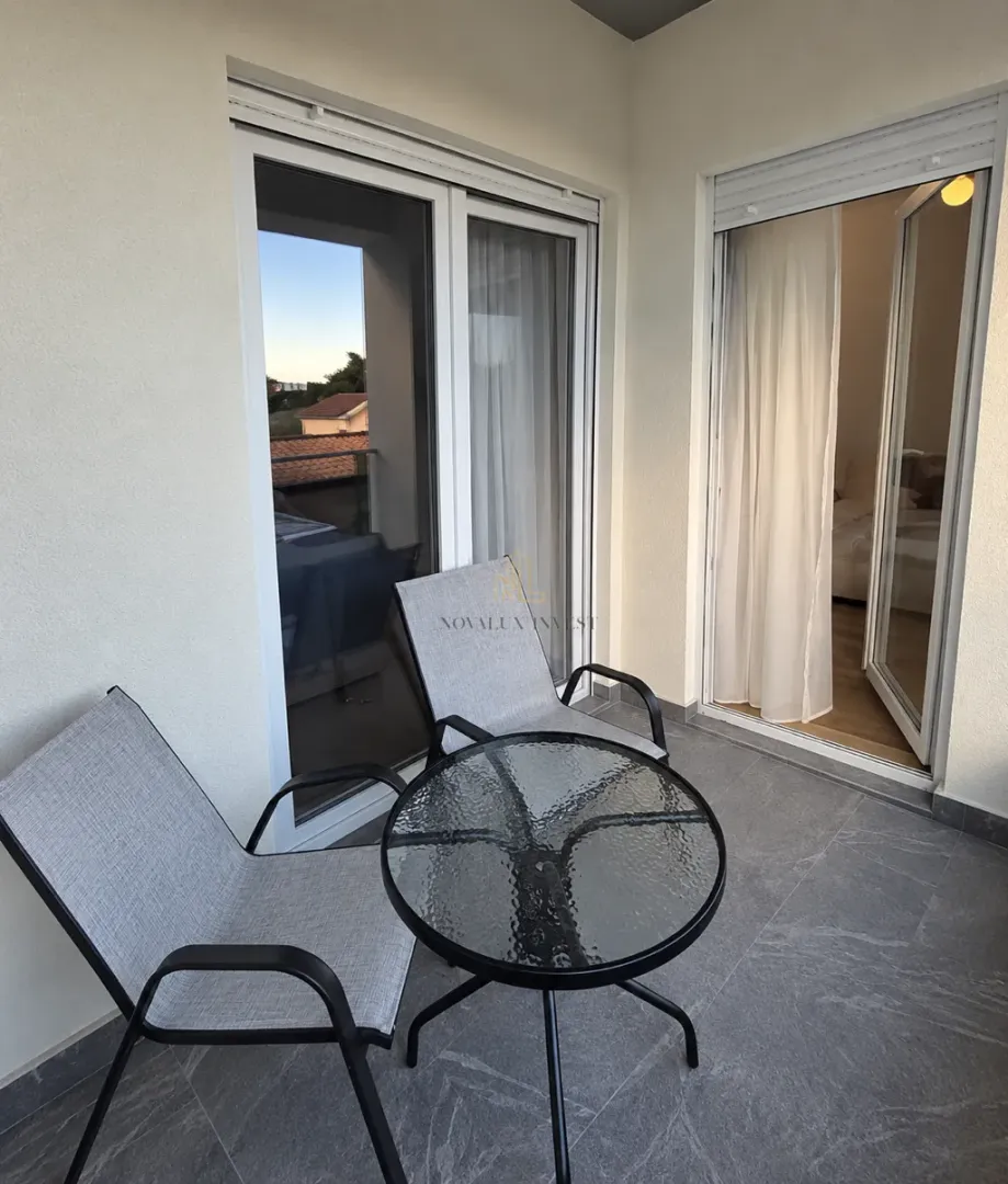 Furnished terrace with a table, two armchairs, and access to the apartment.