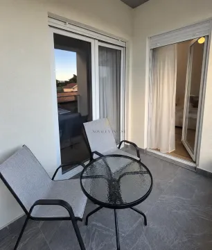 Furnished terrace with a table, two armchairs, and access to the apartment. - image 9