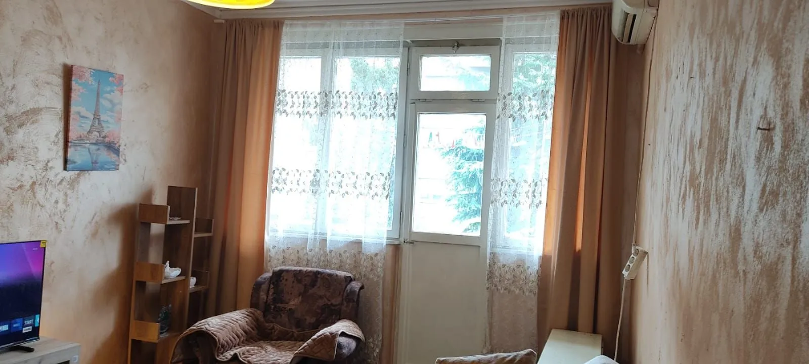 Living room with an armchair, television, and balcony access.