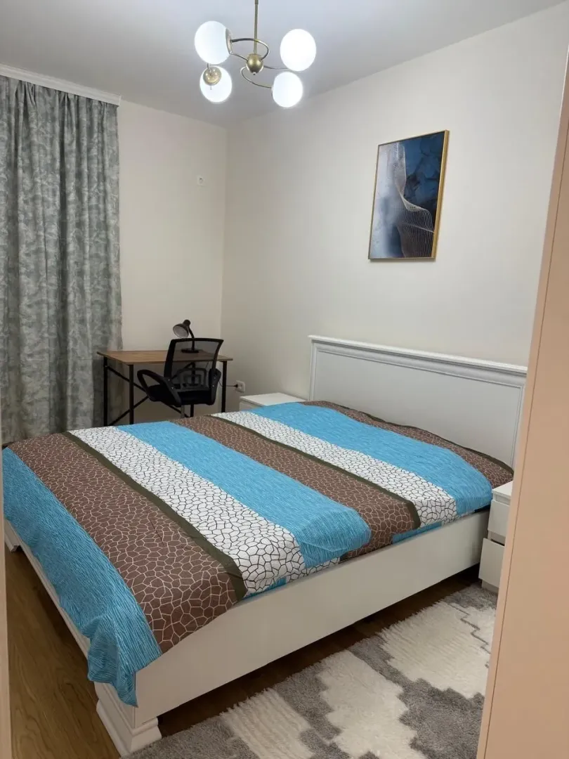 Svijetla spavaća soba sa bračnim krevetom i radnim stolom.