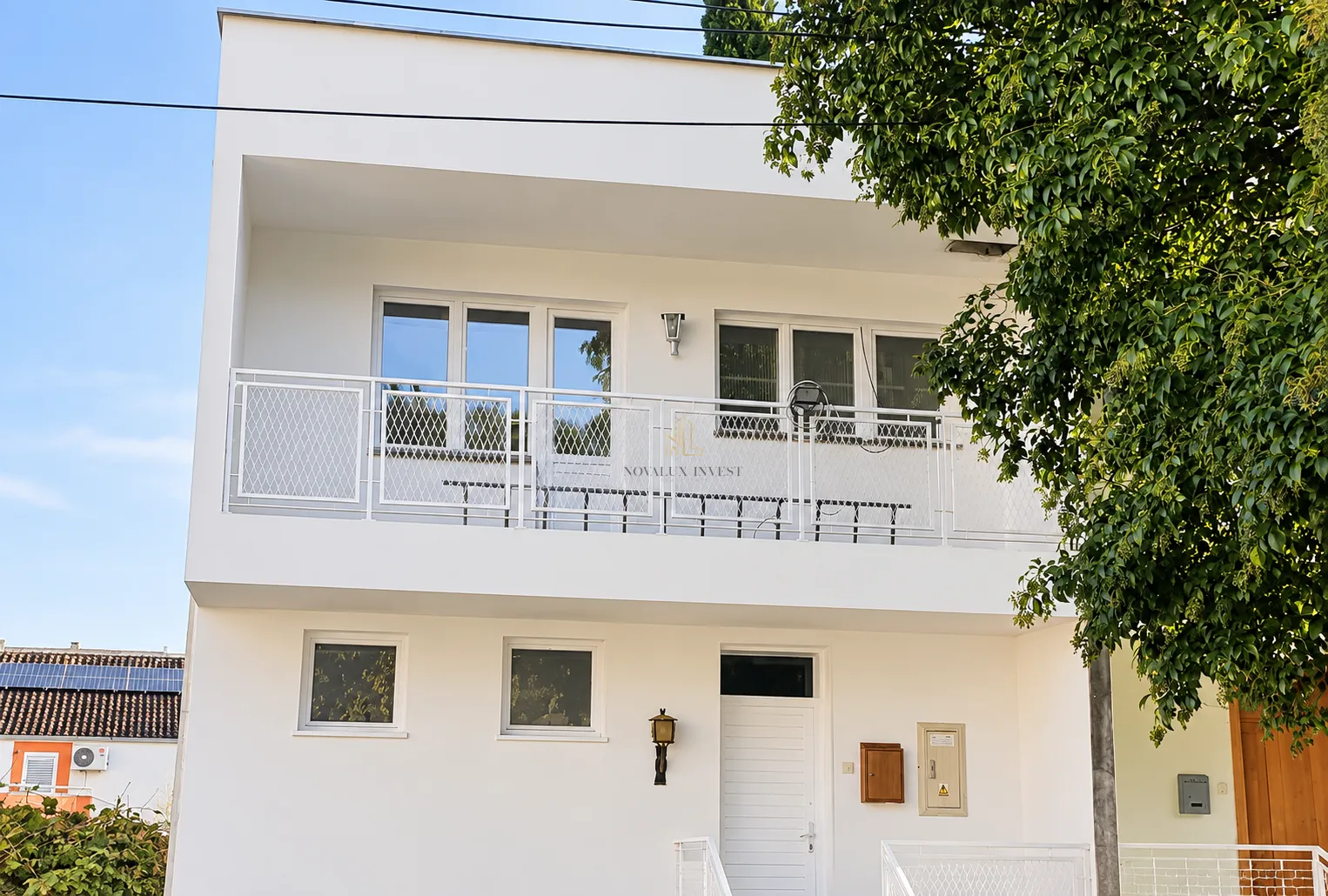 Front view of a modern white building with a terrace.