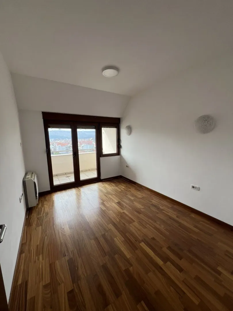 An empty room with wooden flooring and access to a terrace.