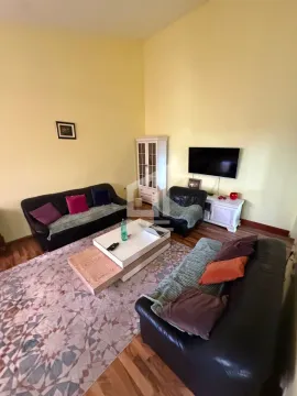 Living room furnished with black leather sofas, a coffee table, and a wall-mounted TV. - image 2