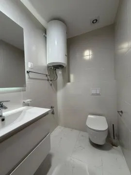 Modernly equipped bathroom with white tiles, washbasin and toilet. - image 9