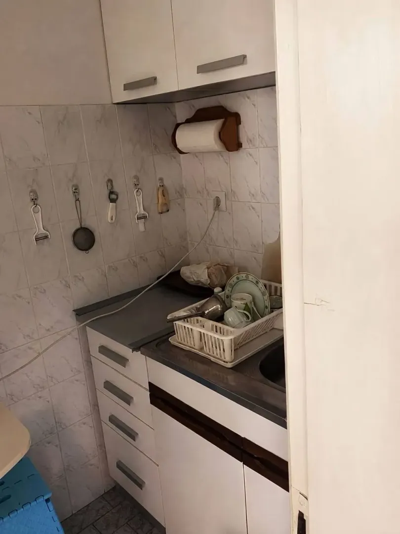 Manja kuhinja sa sudoperom, radnim dijelom i gornjim elementima.