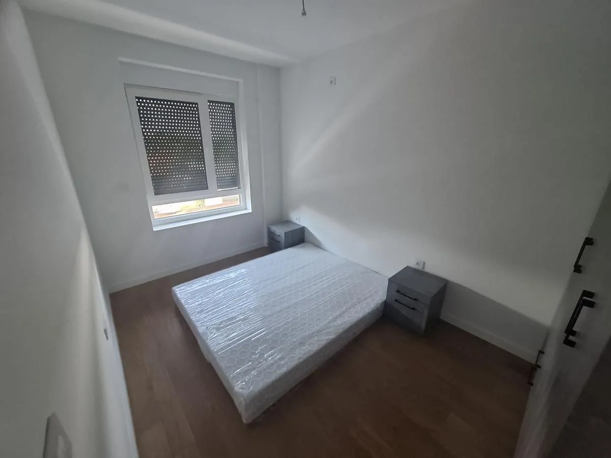 Manja spavaća soba sa krevetom i noćnim stočićima.