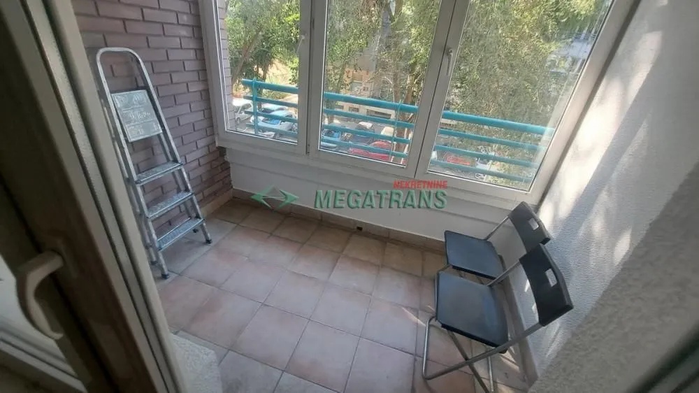 Zastakljeni balkon sa keramičkim pločicama na podu i stolicama.