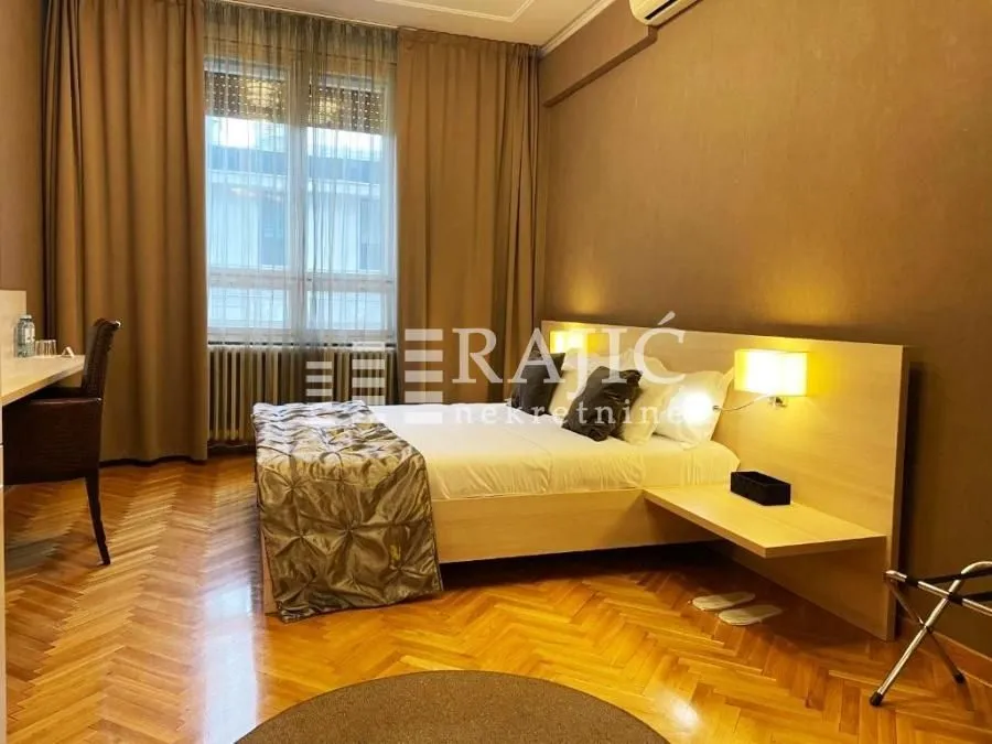 Furnished bedroom with a double bed, desk, and parquet flooring.