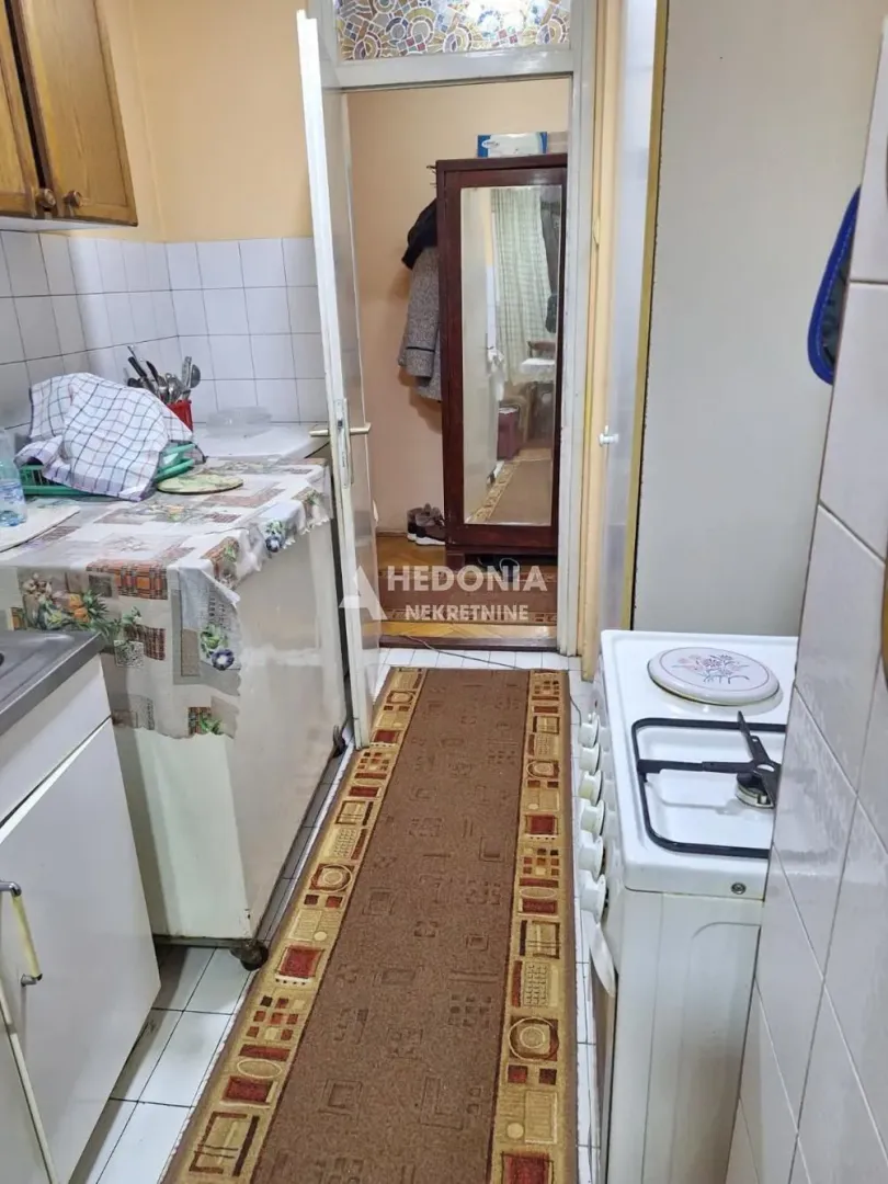Smaller kitchen with a stove, sink, and a passage to the hallway.