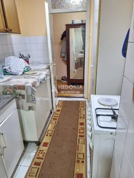Smaller kitchen with a stove, sink, and a passage to the hallway. - image 4