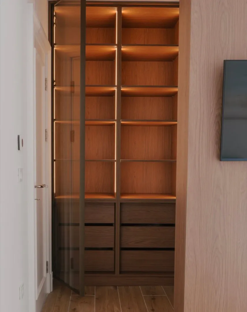 Built-in wooden wardrobe with interior lighting.