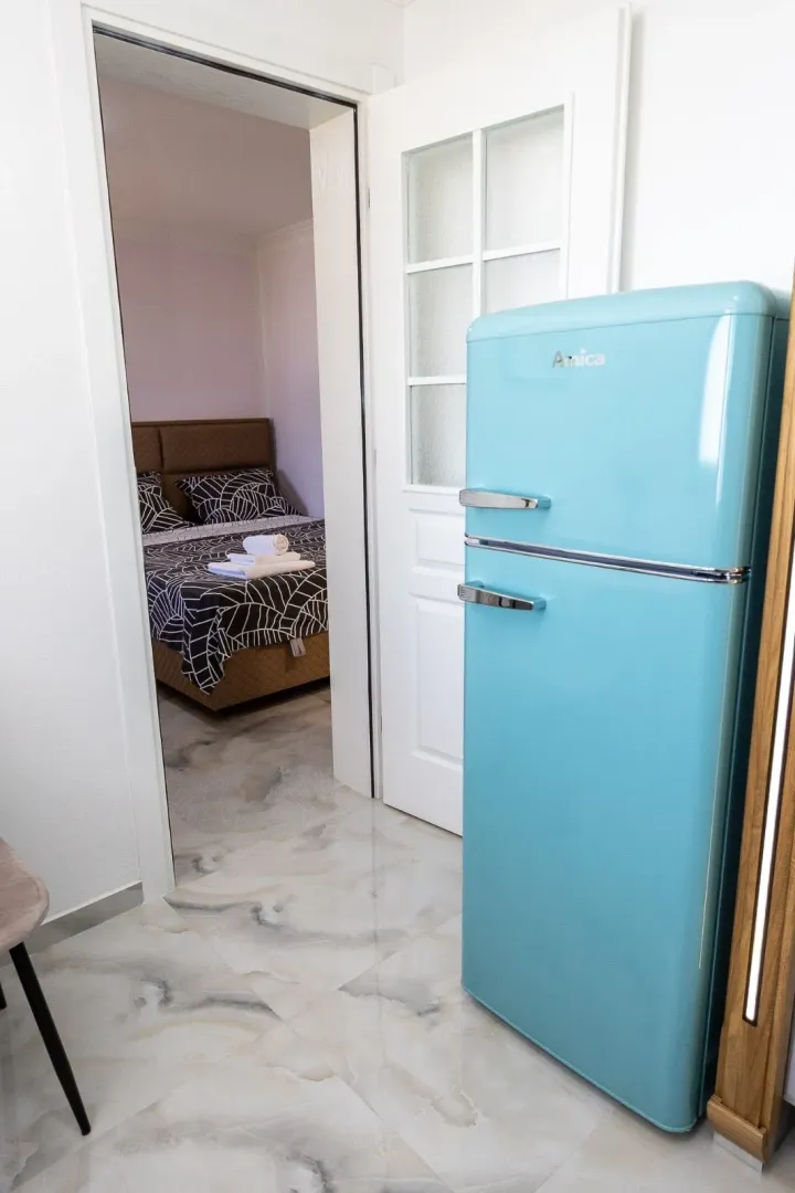 View from the kitchen towards the bedroom with a blue refrigerator.