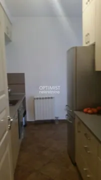 Pogled na usku kuhinju sa elementima i frižiderom. - image 3